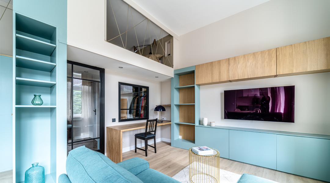 Aménagement intérieur sur mesure avec bibliothèque intégrée bleu pastel et bois, bureau suspendu et mezzanine dans un appartement moderne à Lille