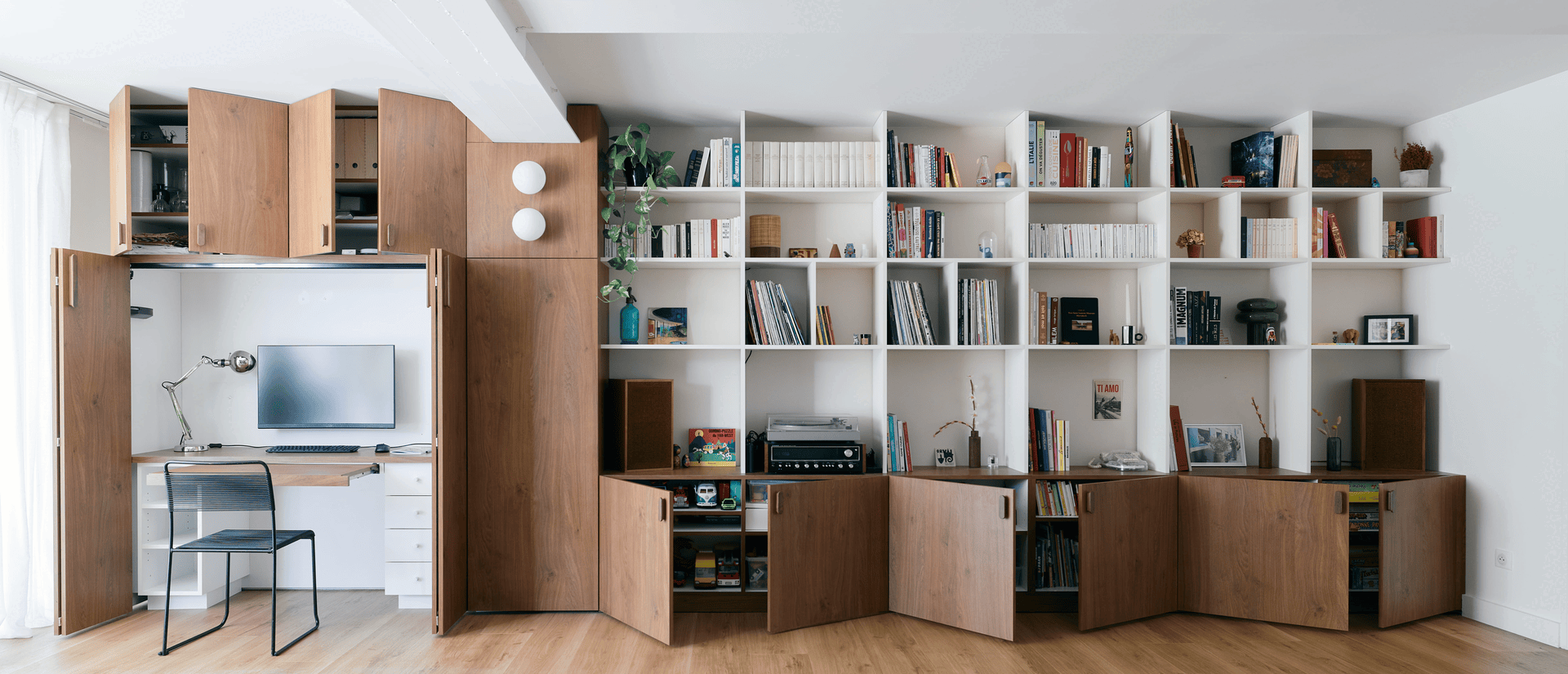 Agencement sur mesure à Lille : bureau escamotable dissimulé dans une bibliothèque en bois et blanc